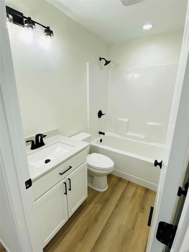 full bathroom with wood finished floors, toilet, shower / bath combination, vanity, and recessed lighting