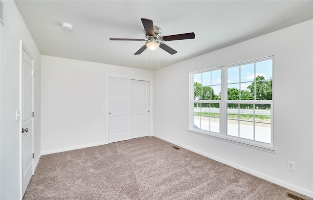spare room with carpet, baseboards, and a ceiling fan