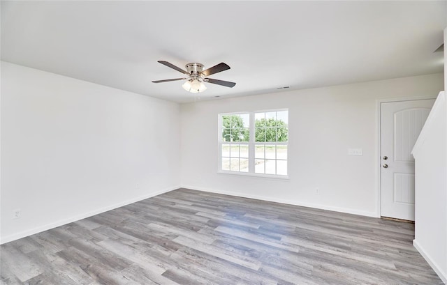 empty room with a ceiling fan, wood finished floors, and baseboards