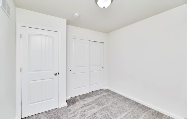 unfurnished bedroom featuring light carpet, a closet, and baseboards