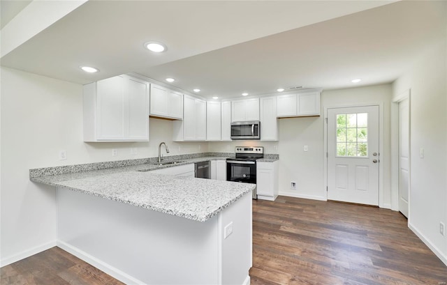 kitchen with appliances with stainless steel finishes, a peninsula, a sink, white cabinetry, and recessed lighting