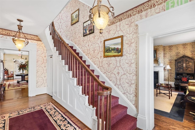 813 S 4th St, Clarksville, MO 63336 - staircase with wallpapered walls, wood finished floors, a fireplace, and baseboards