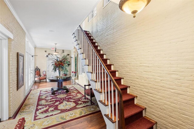 813 S 4th St, Clarksville, MO 63336 - staircase featuring brick wall, crown molding, and wood finished floors
