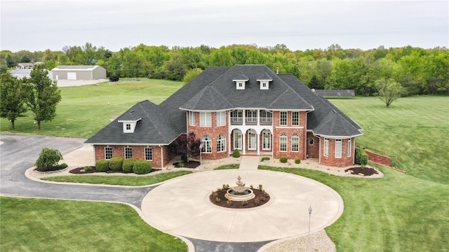 rear view of house with brick siding, curved driveway, and a yard