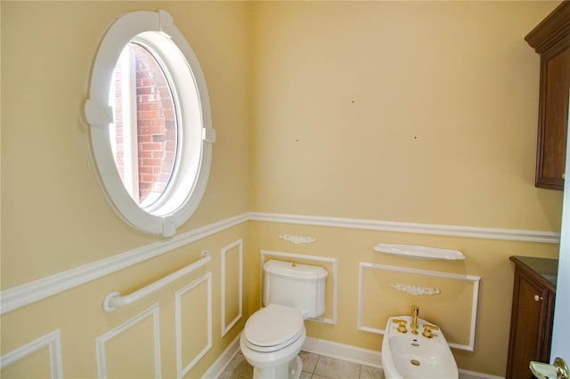 bathroom with toilet, a bidet, tile patterned flooring, and vanity