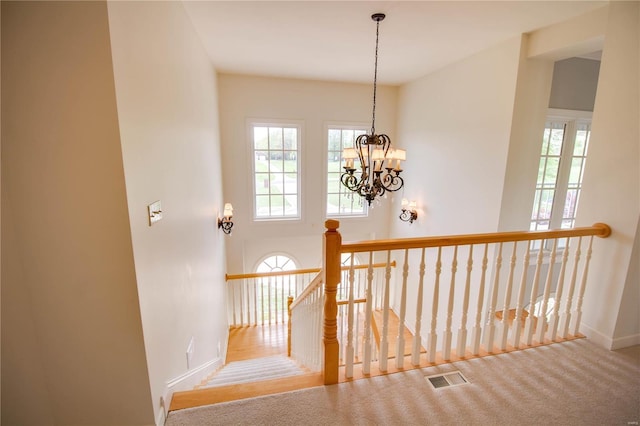 stairway featuring baseboards, a chandelier, and carpet