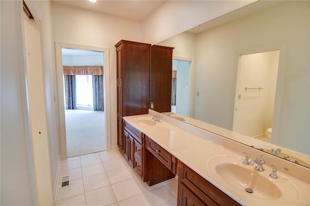 full bath featuring toilet, double vanity, and tile patterned flooring