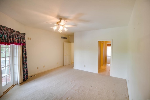 spare room featuring light carpet, plenty of natural light, a ceiling fan, and baseboards