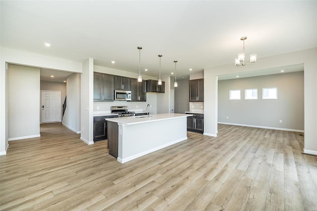 kitchen featuring stainless steel appliances, open floor plan, light wood-type flooring, a chandelier, and light countertops
