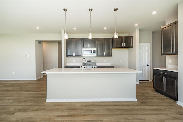 kitchen with appliances with stainless steel finishes, baseboards, light countertops, light wood-style flooring, and a sink