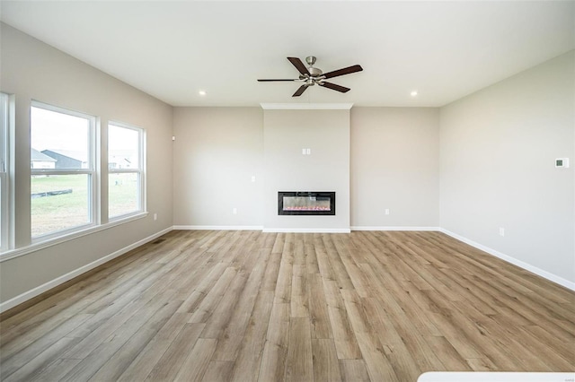 unfurnished living room featuring baseboards, light wood-style flooring, a ceiling fan, recessed lighting, and a glass covered fireplace