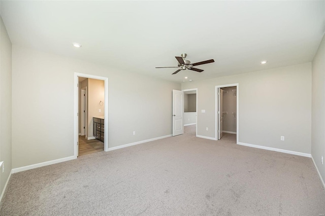 unfurnished bedroom featuring light carpet, baseboards, a spacious closet, recessed lighting, and a ceiling fan