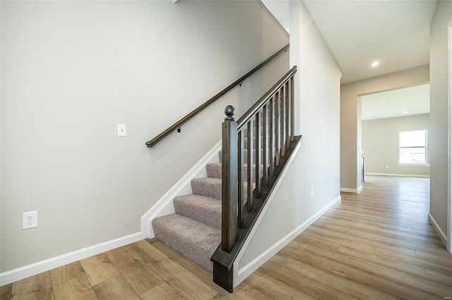 stairs featuring wood finished floors, baseboards, and recessed lighting