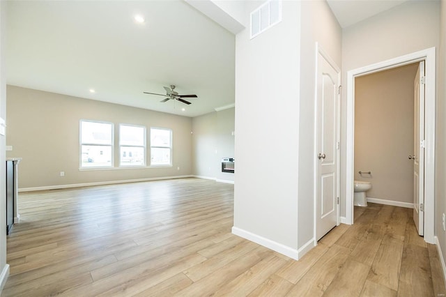 unfurnished living room featuring a ceiling fan, light wood-type flooring, baseboards, recessed lighting, and a glass covered fireplace