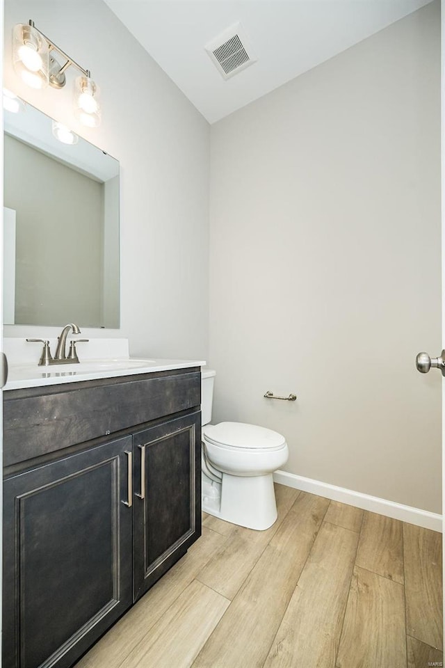 bathroom featuring wood finished floors, toilet, vanity, and baseboards