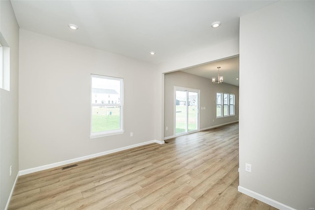spare room featuring a chandelier, light wood-type flooring, baseboards, and recessed lighting