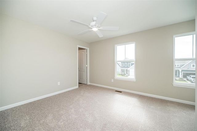 empty room featuring a ceiling fan, baseboards, and light colored carpet