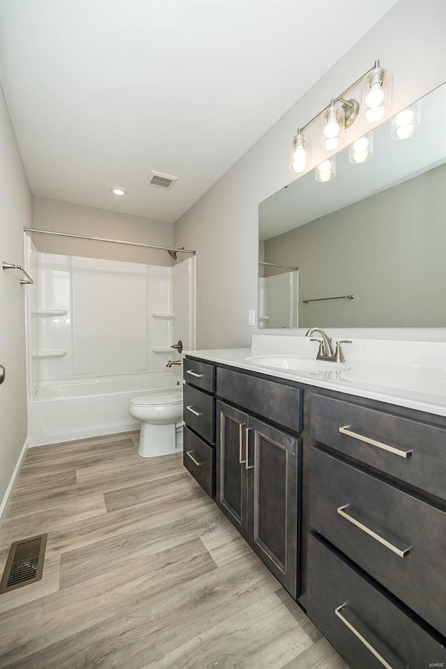 bathroom featuring vanity, tub / shower combination, wood finished floors, and toilet