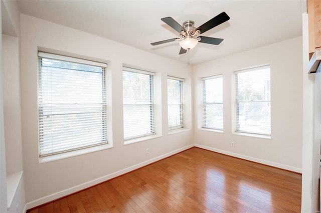 unfurnished room featuring baseboards, wood-type flooring, plenty of natural light, and a ceiling fan