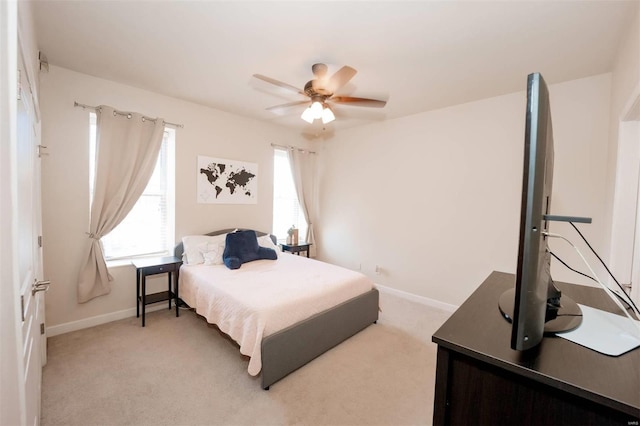 bedroom featuring baseboards, light colored carpet, and a ceiling fan