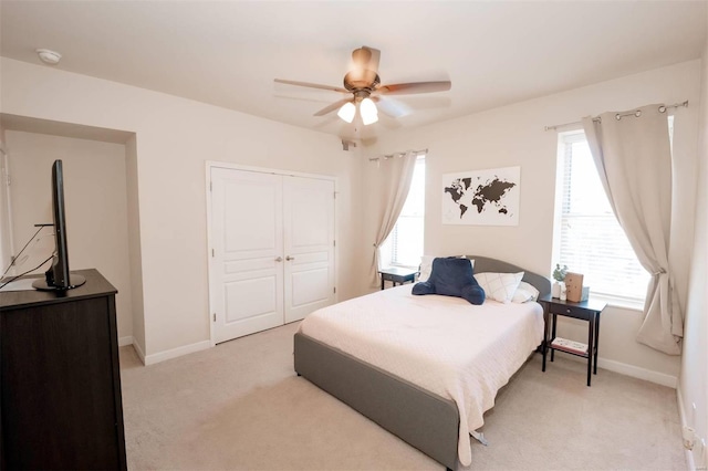 bedroom featuring light carpet, a closet, and multiple windows