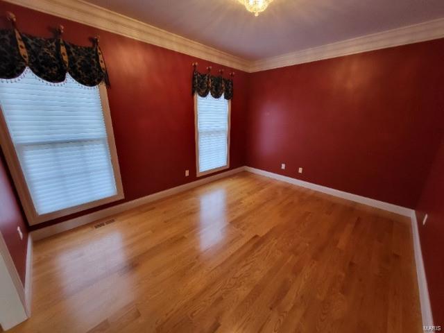 unfurnished room featuring light wood-type flooring, baseboards, and ornamental molding
