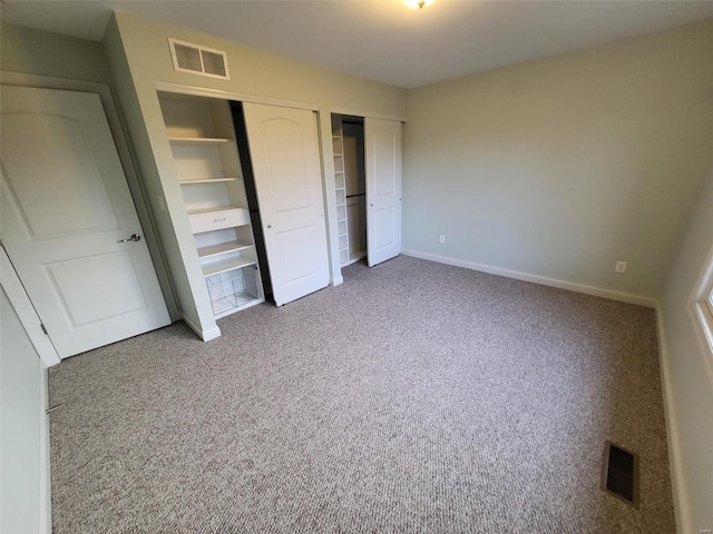 unfurnished bedroom with two closets, carpet floors, and baseboards
