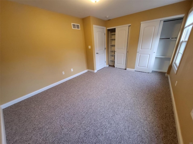 unfurnished bedroom with two closets, carpet, and baseboards