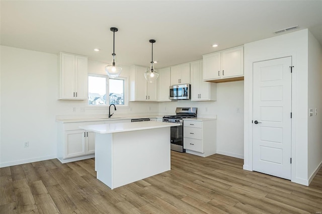 1909 Rolling River Cir, Ofallon, MO 63366 - kitchen with appliances with stainless steel finishes, a sink, recessed lighting, light wood finished floors, and white cabinets