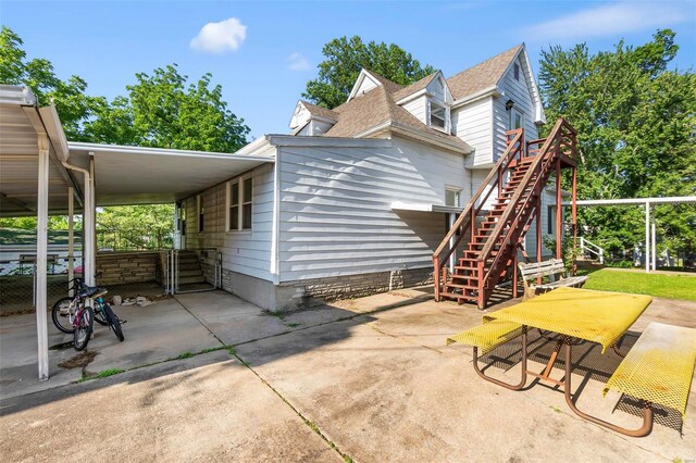 rear view of property with stairs and a shingled roof