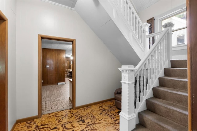 stairway featuring baseboards and lofted ceiling