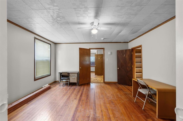 unfurnished bedroom with ornamental molding, wood-type flooring, multiple windows, an office area, and baseboards