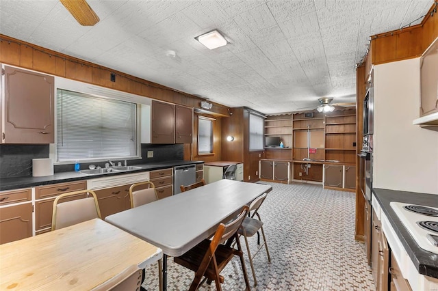 kitchen featuring a ceiling fan, a sink, dark countertops, stainless steel appliances, and decorative backsplash