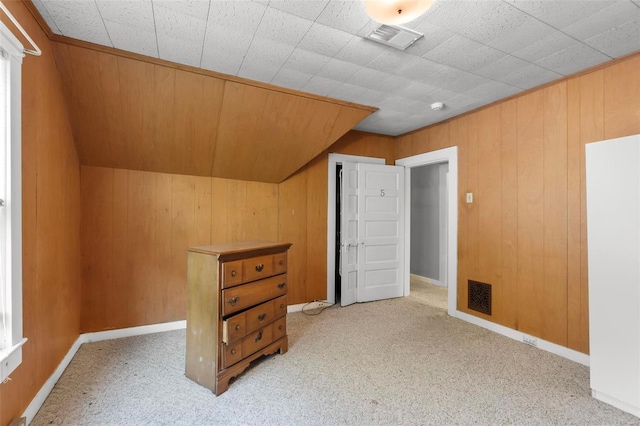 bonus room with light carpet and wood walls