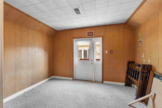 carpeted entryway with wood walls and baseboards