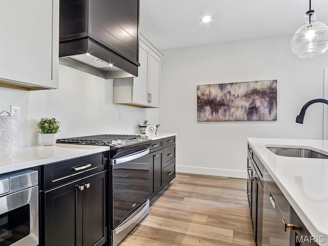 3106 Ashley Dr, Glen Carbon, IL 62034 - kitchen with stainless steel range with gas stovetop, a sink, light wood-style floors, light countertops, and wall chimney exhaust hood