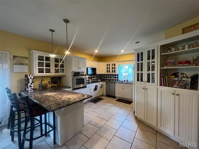 1001 S Main St, Lockwood, MO 65682 - kitchen featuring stainless steel appliances, a peninsula, glass insert cabinets, a breakfast bar area, and white cabinets