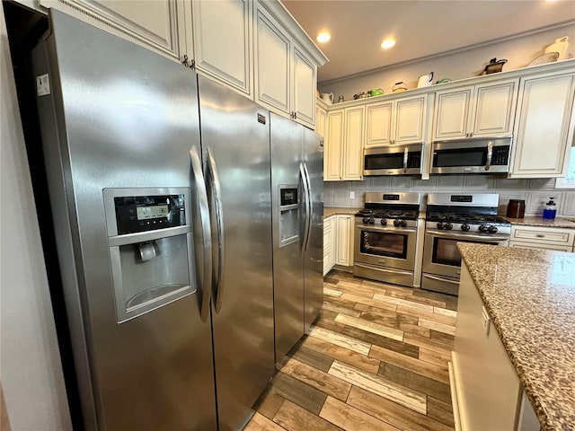 14305 State Highway F, Canton, MO 63435 - kitchen with appliances with stainless steel finishes, light wood-style flooring, light stone counters, decorative backsplash, and recessed lighting