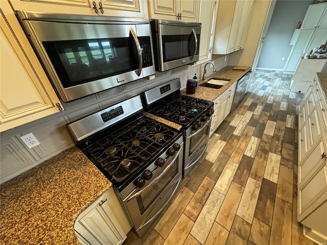 14305 State Highway F, Canton, MO 63435 - kitchen featuring appliances with stainless steel finishes, a sink, cream cabinetry, wood finished floors, and dark stone counters