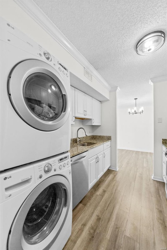 1509 Swallow Dr, Saint Louis, MO 63144 - clothes washing area with estacked washer and dryer, ornamental molding, a chandelier, a textured ceiling, and light wood finished floors
