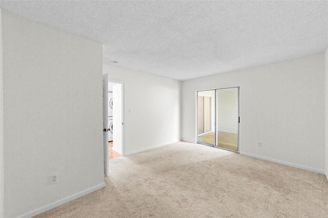 1509 Swallow Dr, Saint Louis, MO 63144 - empty room with stacked washer / drying machine, carpet floors, baseboards, and a textured ceiling