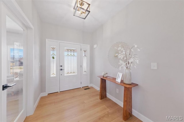 entrance foyer with light wood-style flooring, baseboards, and a chandelier