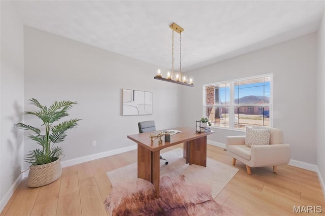 office space with light wood-type flooring, baseboards, and a chandelier