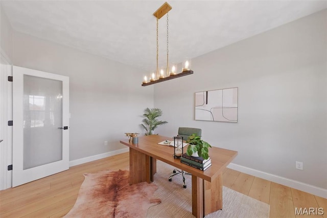home office with light wood-type flooring, baseboards, and a chandelier