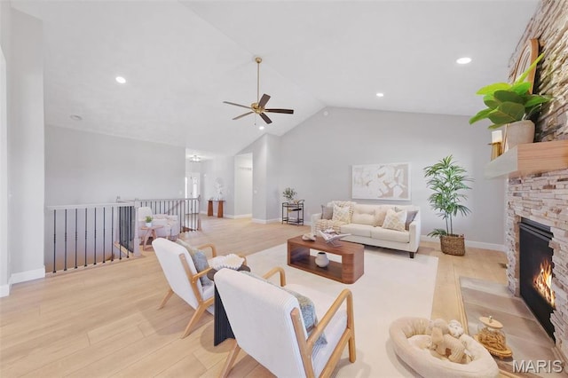 living room with wood finished floors, lofted ceiling, a ceiling fan, a stone fireplace, and recessed lighting