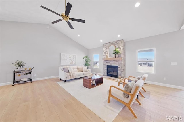living room featuring a ceiling fan, light wood-style flooring, a stone fireplace, high vaulted ceiling, and recessed lighting