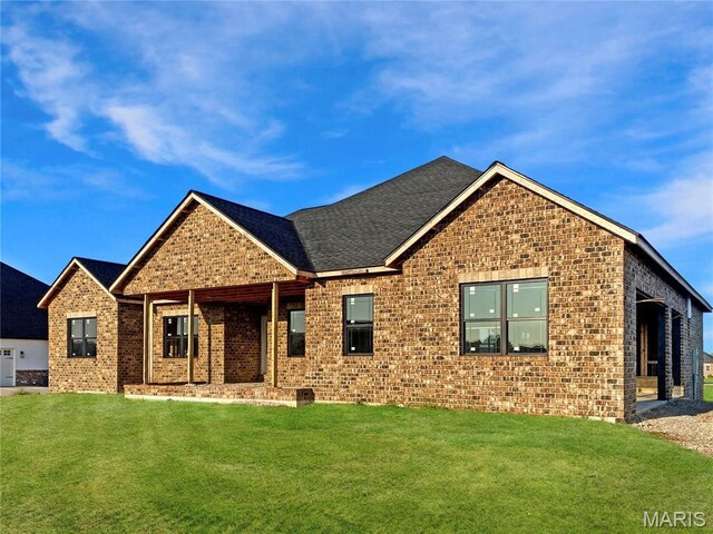 view of front of property featuring brick siding, a front lawn, and a shingled roof