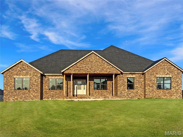 view of front facade featuring brick siding, a front yard, and roof with shingles