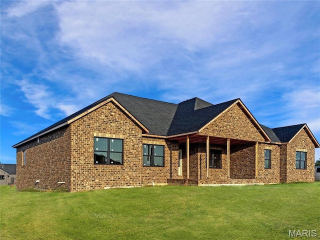 view of front facade featuring a front lawn, brick siding, and a shingled roof