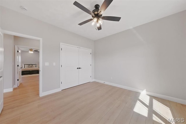 unfurnished bedroom with light wood-type flooring, baseboards, a closet, and a ceiling fan
